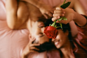 uma mulher deitada em uma cama com uma rosa na mão