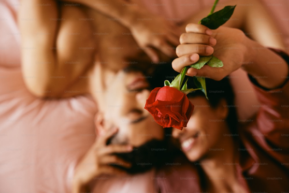 a woman laying on a bed with a rose in her hand