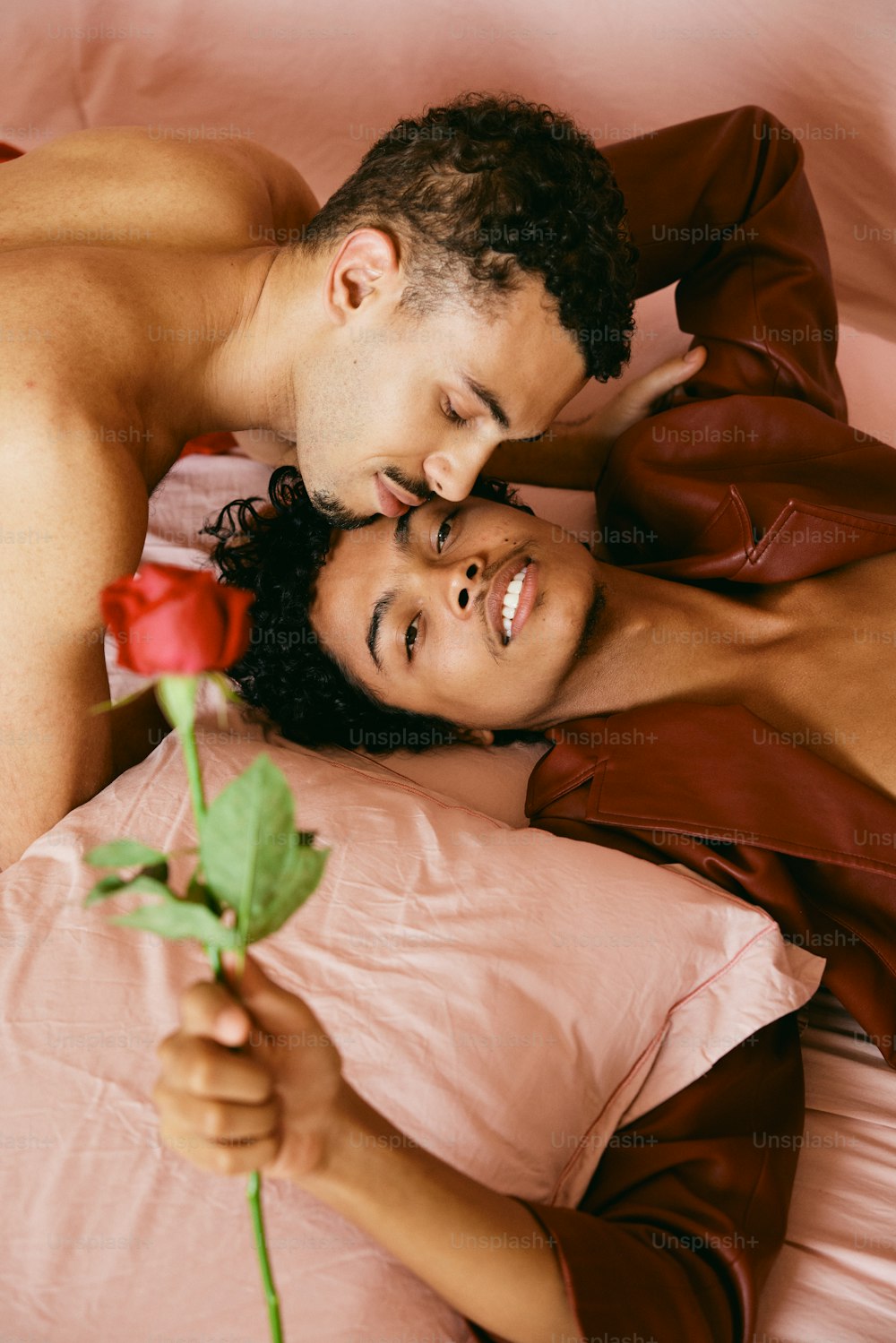 a man and woman laying in bed with a rose
