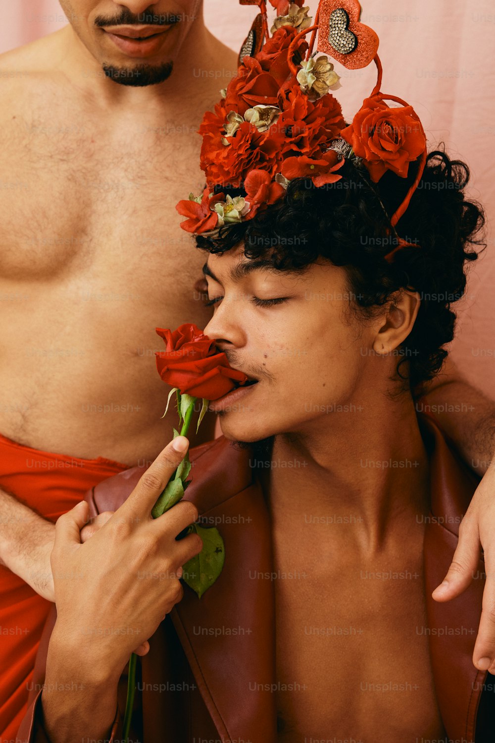 un uomo a torso nudo con una corona di fiori in testa