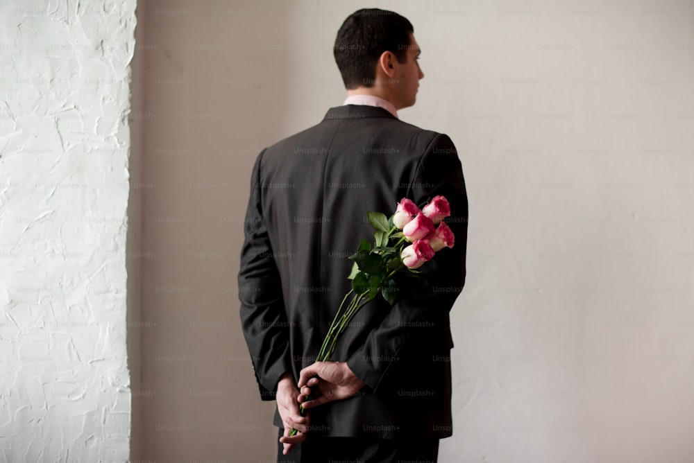 a man in a suit holding a bouquet of flowers