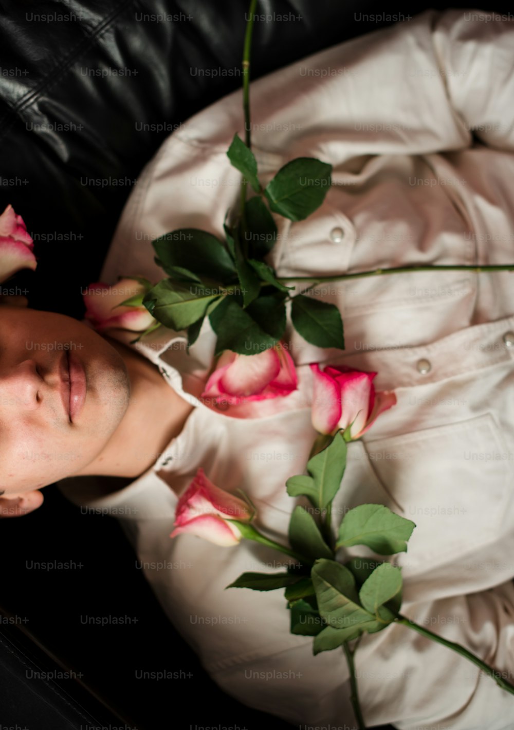 a man laying on a couch with flowers in his lap