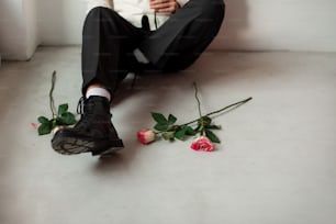 a man in a tuxedo sitting on the floor next to roses