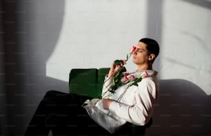 a man sitting on a green chair with a flower in his hand