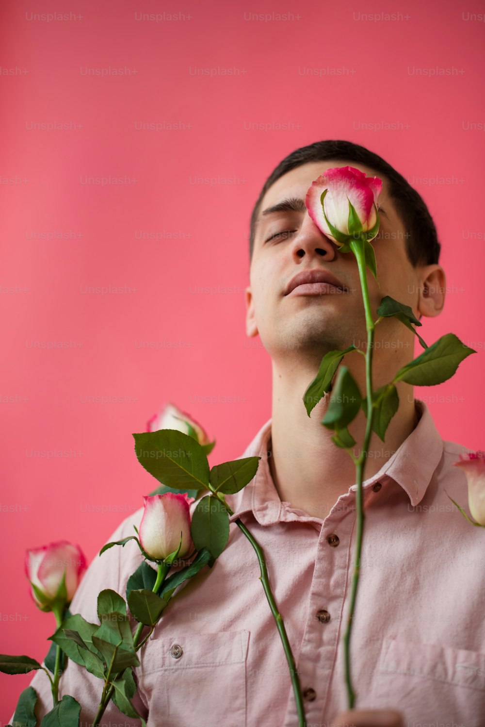 a man holding a bunch of roses in front of his face