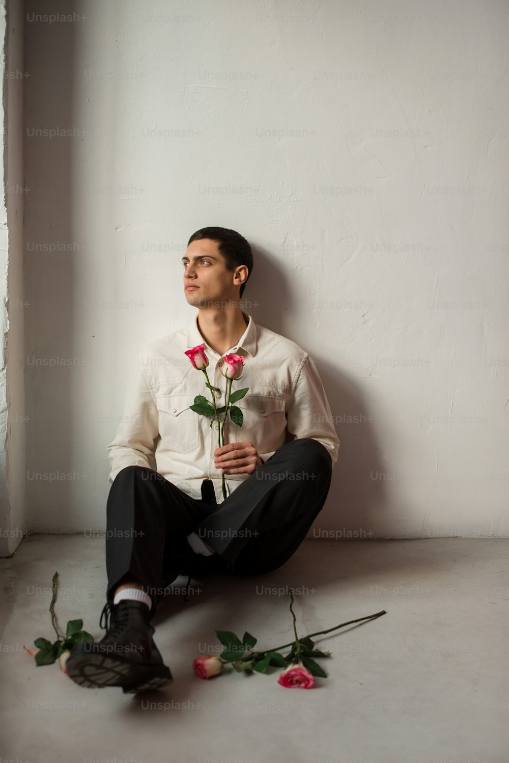 a man sitting on the floor with a rose in his lap