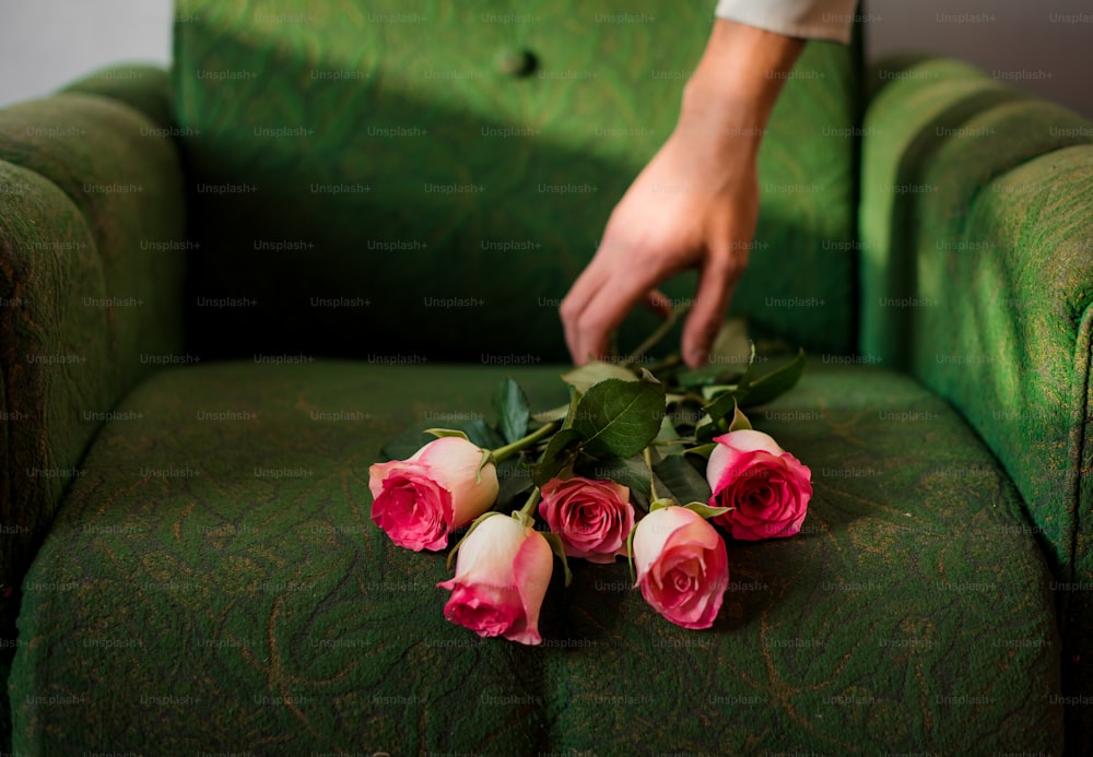 a person arranging roses on a green couch