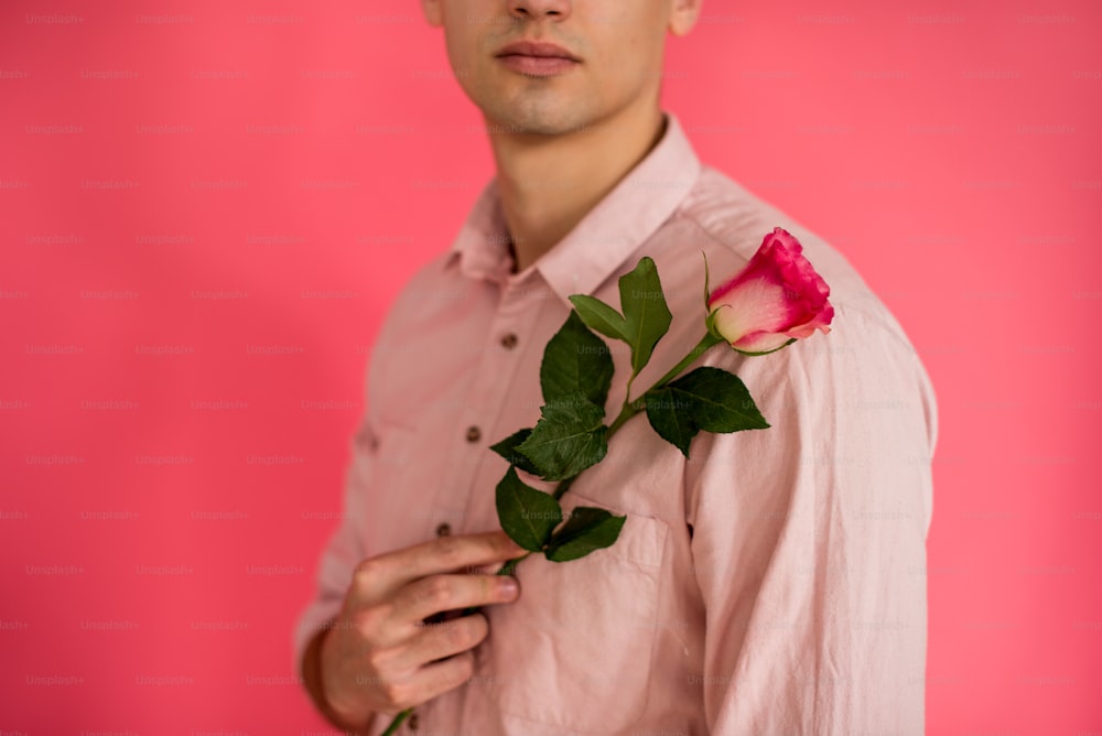 ピンクのシャツを着た男性がバラの花を咲かせています