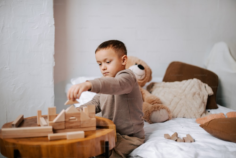 a young boy playing with wooden blocks on a bed