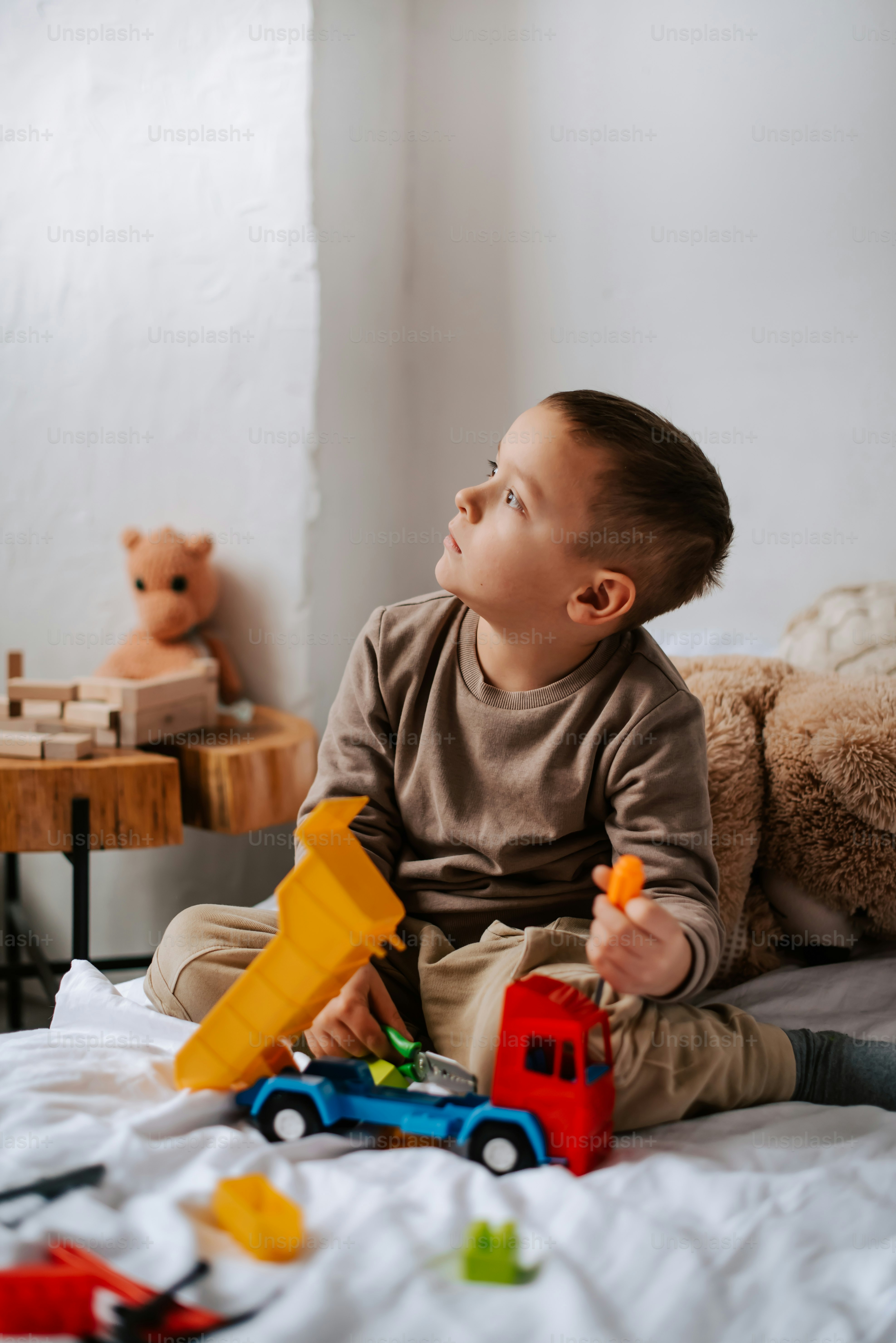 a little boy sitting on a bed playing with toys