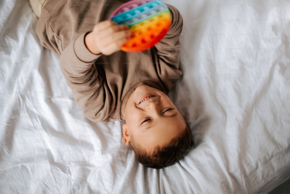 a young child laying on a bed holding a toy