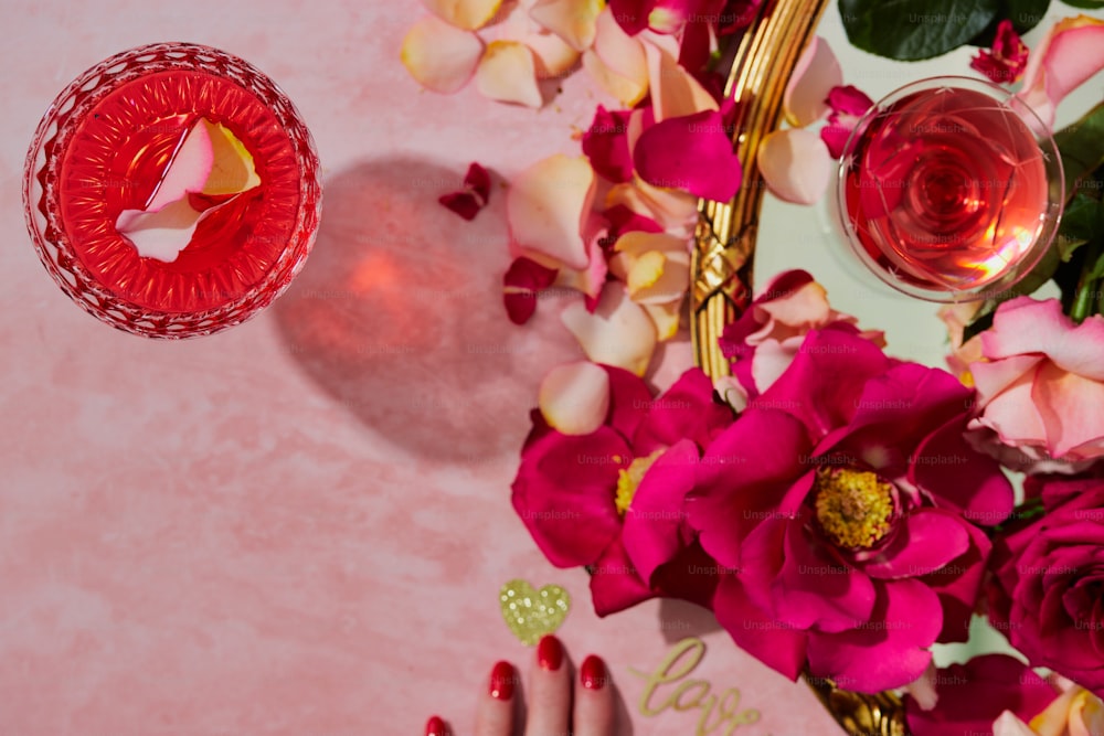 une main de femme avec du vernis à ongles rouge à côté d’un vase de fleurs