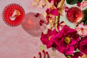 a woman's hand with red nail polish next to a vase of flowers