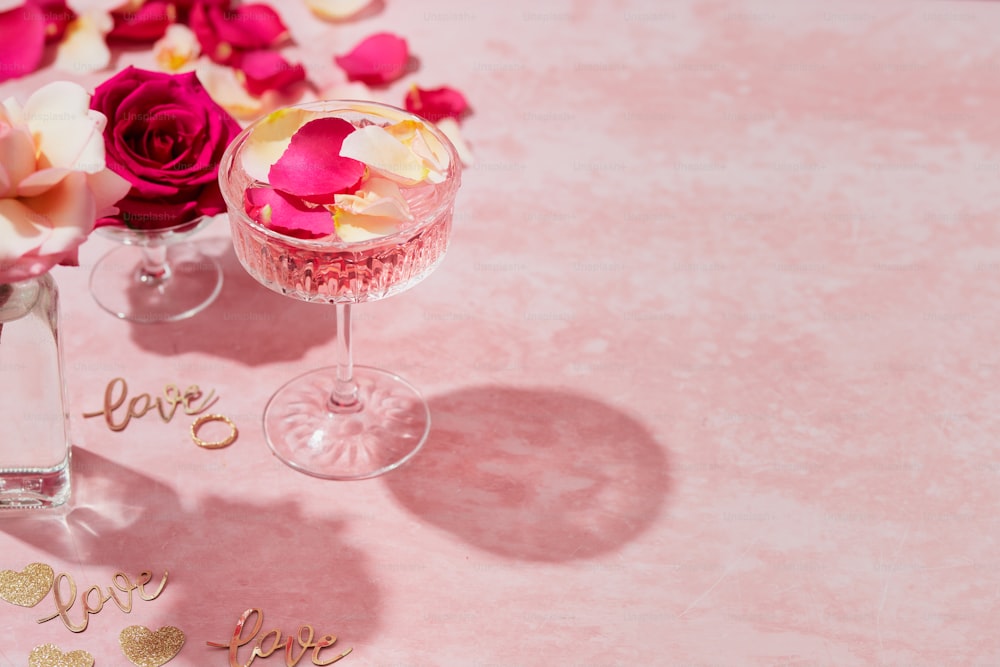 분홍색 테이블 위에 꽃이 가득한 와인잔 2개