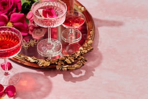 a pink table topped with wine glasses and flowers