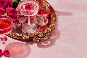 uma mesa rosa coberta com taças de vinho e flores