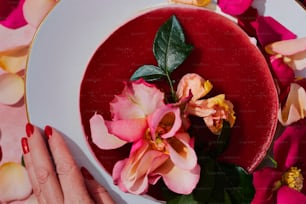 a woman's hand holding a plate with flowers on it