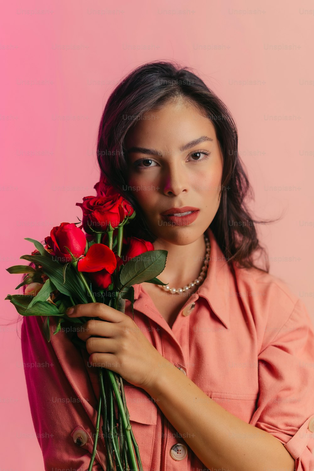 una mujer sosteniendo un ramo de rosas rojas