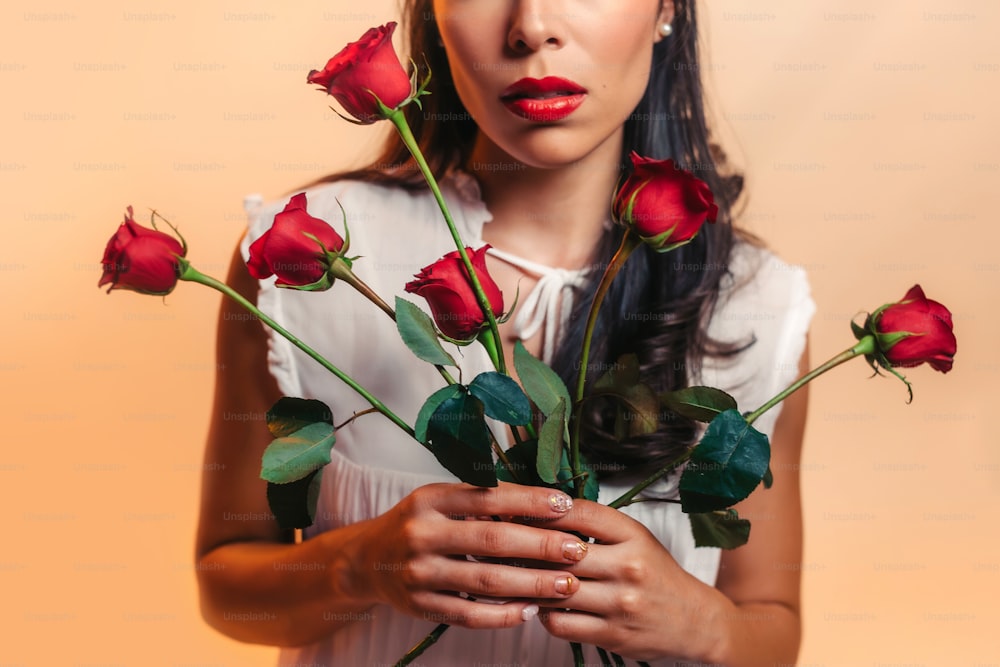 a woman holding a bunch of roses in her hands