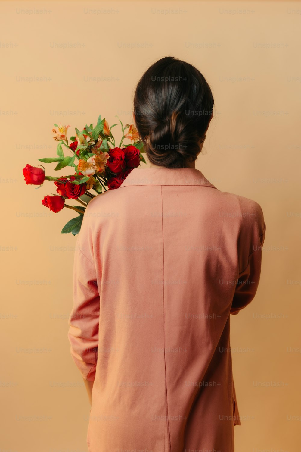 uma mulher em uma jaqueta rosa segurando um buquê de flores