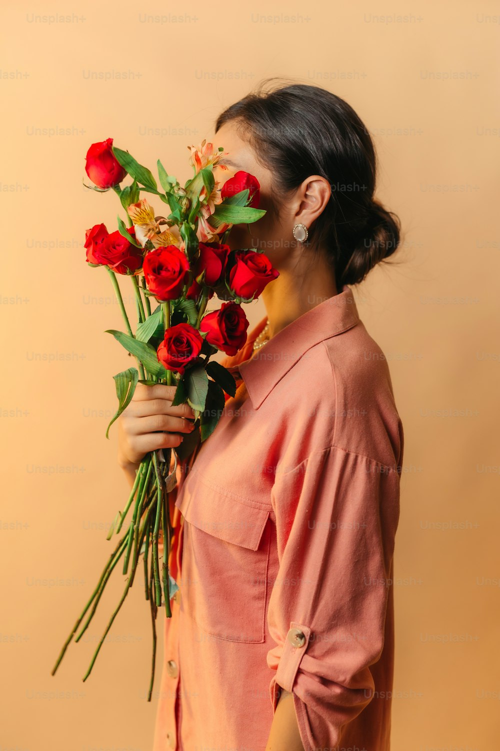 eine Frau hält einen Strauß roter Rosen in der Hand