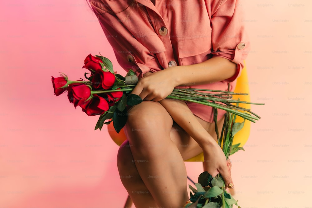 a woman sitting on a chair holding a bunch of roses