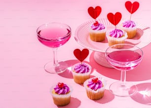 cupcakes and a glass of wine on a pink background