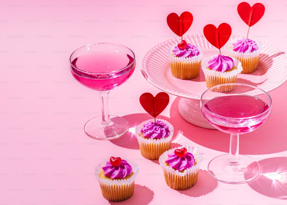 cupcakes et un verre de vin sur fond rose