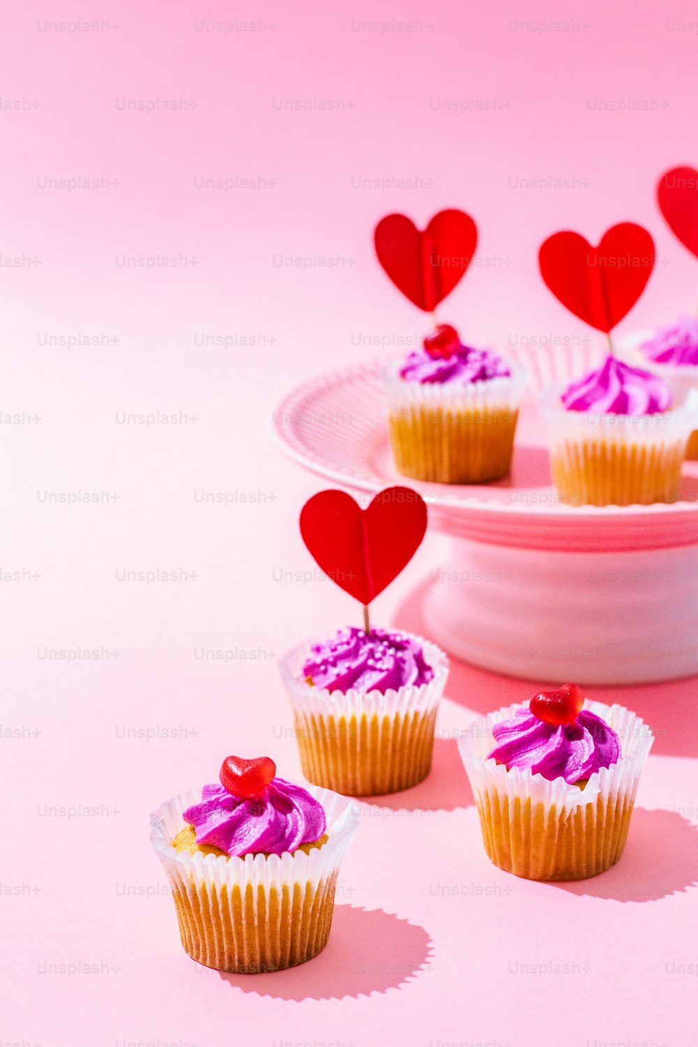 접시에 분홍색 설탕 프로스팅과 하트를 곁들인 컵케이크