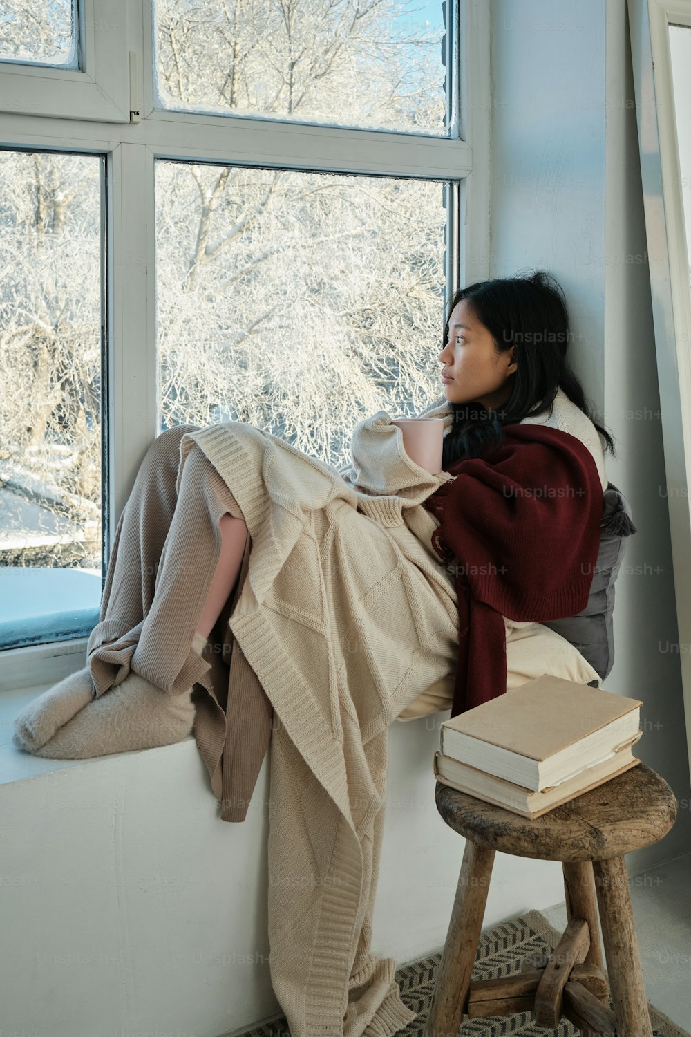 a woman sitting on a window sill next to a book
