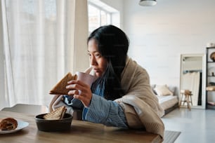 a woman sitting at a table eating a sandwich