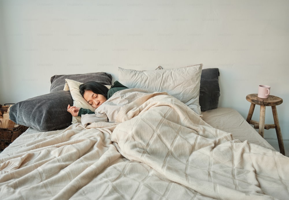 a woman laying in bed with a pillow and blanket