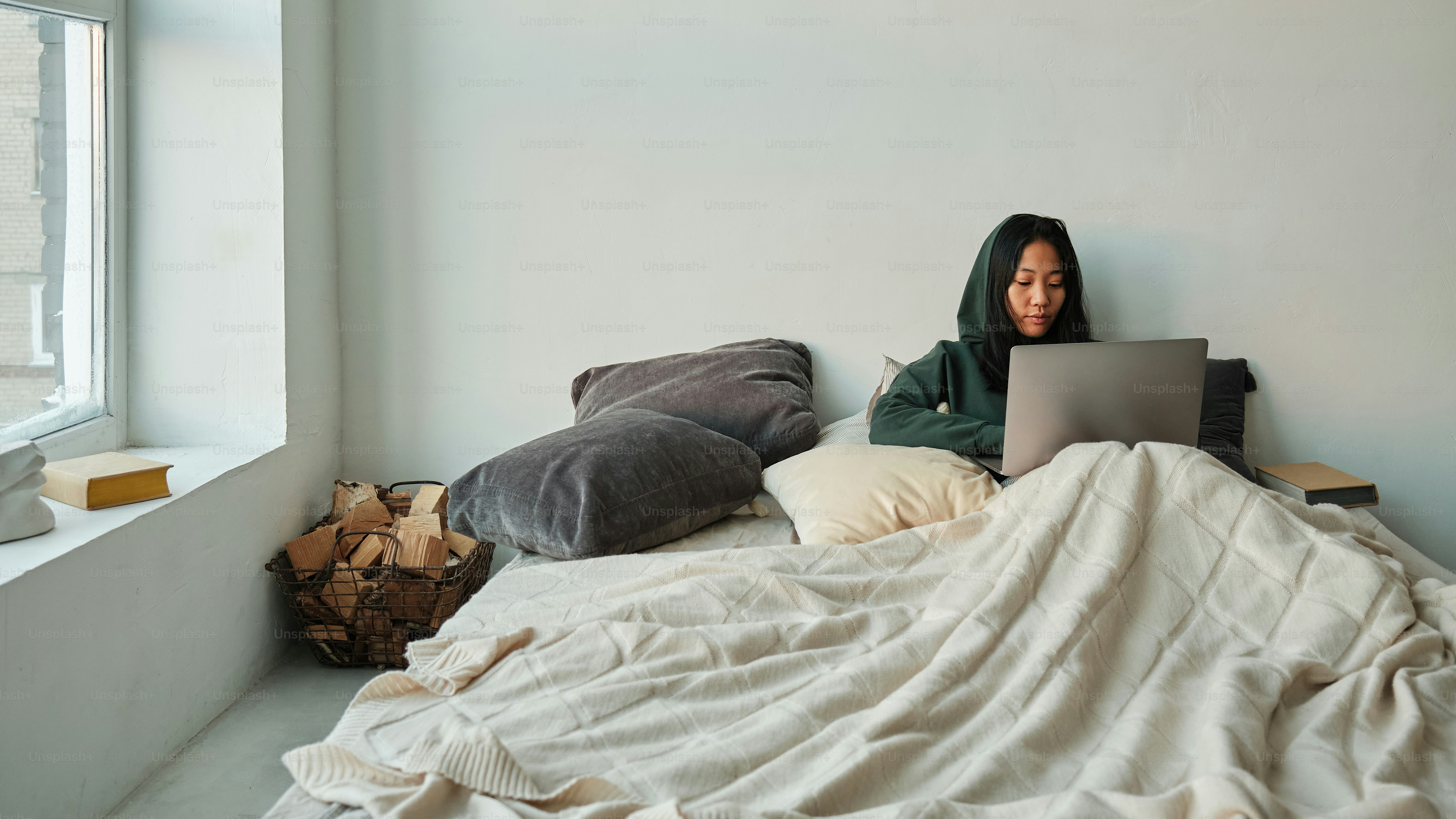 seorang wanita duduk di tempat tidur dengan laptop