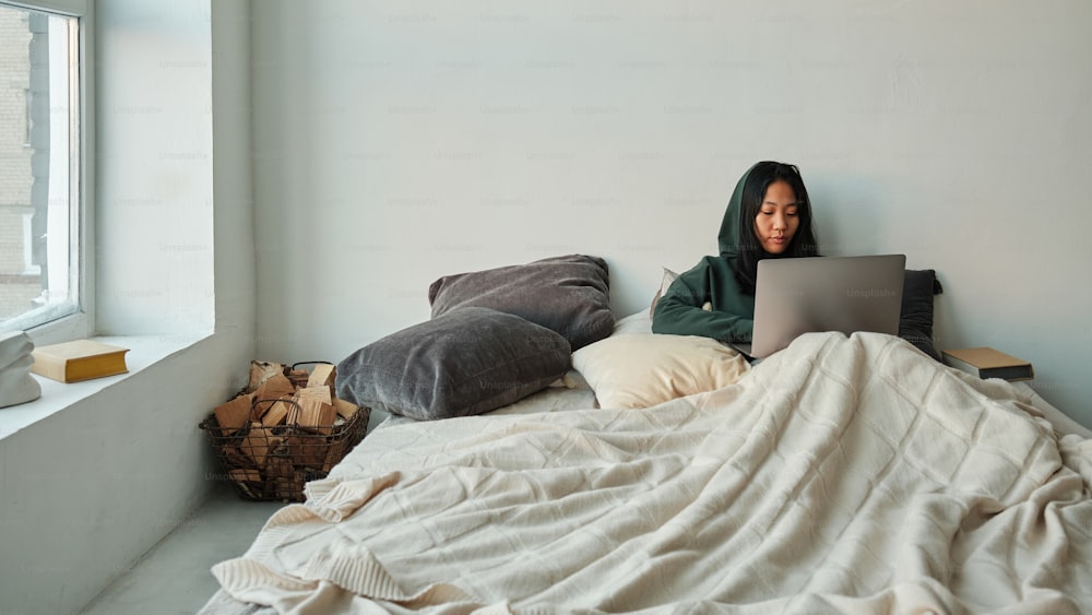 a woman sitting on a bed with a laptop