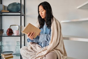 a woman sitting on a chair reading a book