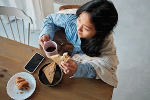 a woman sitting at a table with a plate of food and a cup of coffee