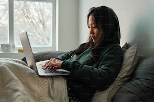 a woman sitting on a bed using a laptop computer