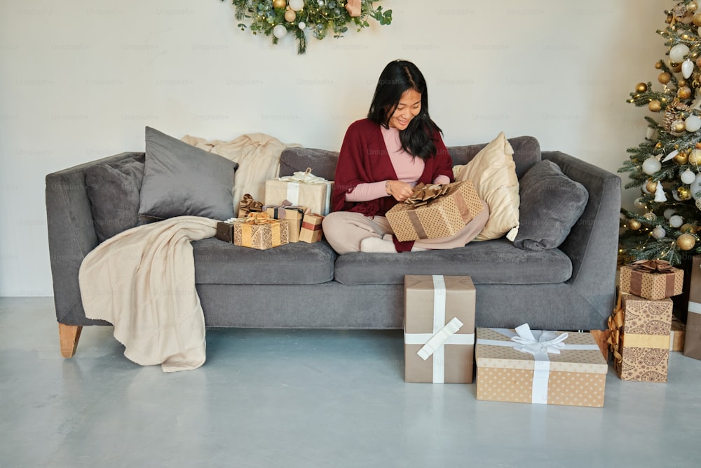 a woman sitting on a couch surrounded by presents