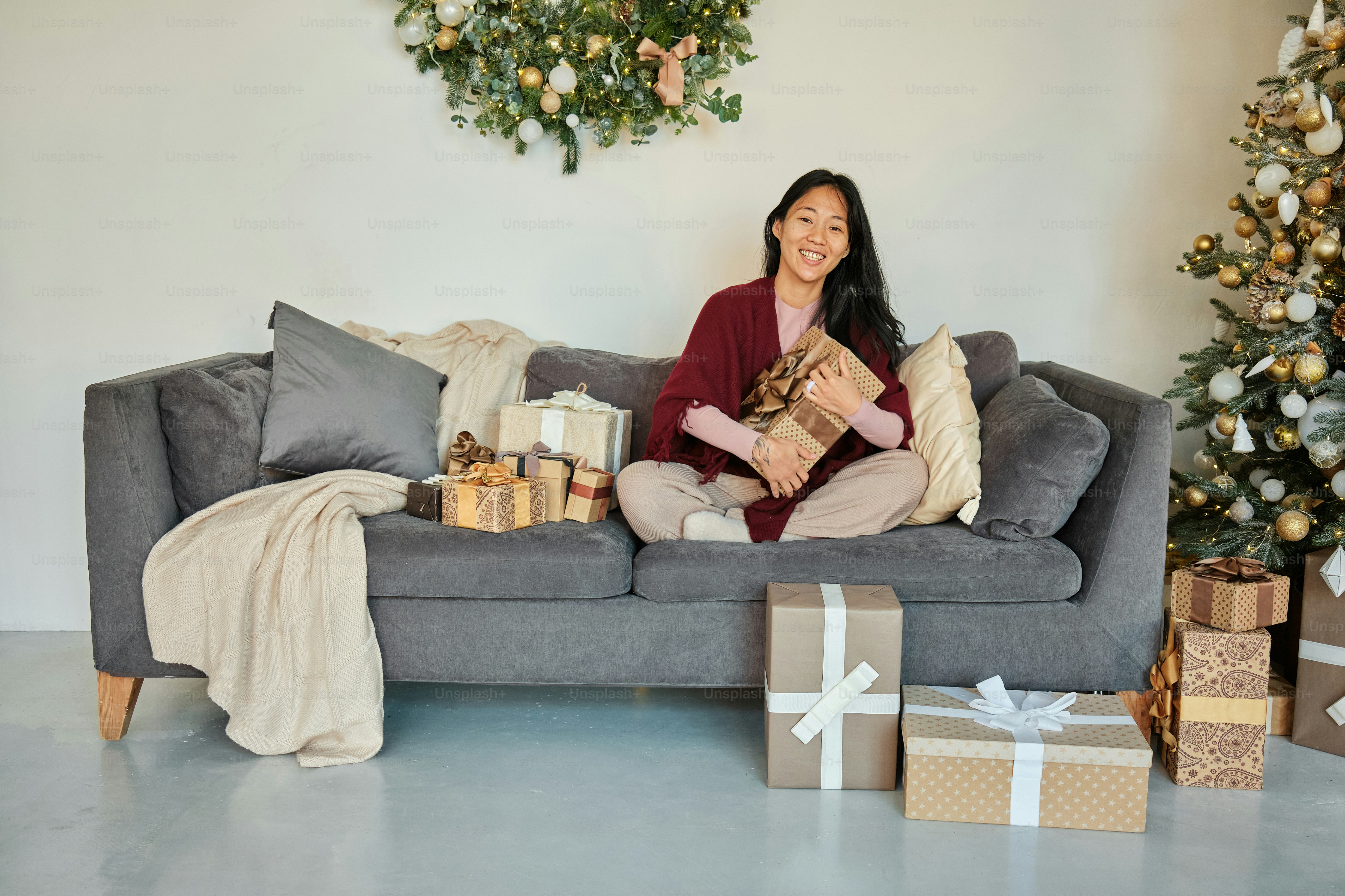 seorang wanita duduk di sofa dengan hadiah di depannya