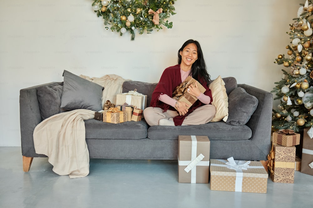 a woman sitting on a couch with presents in front of her