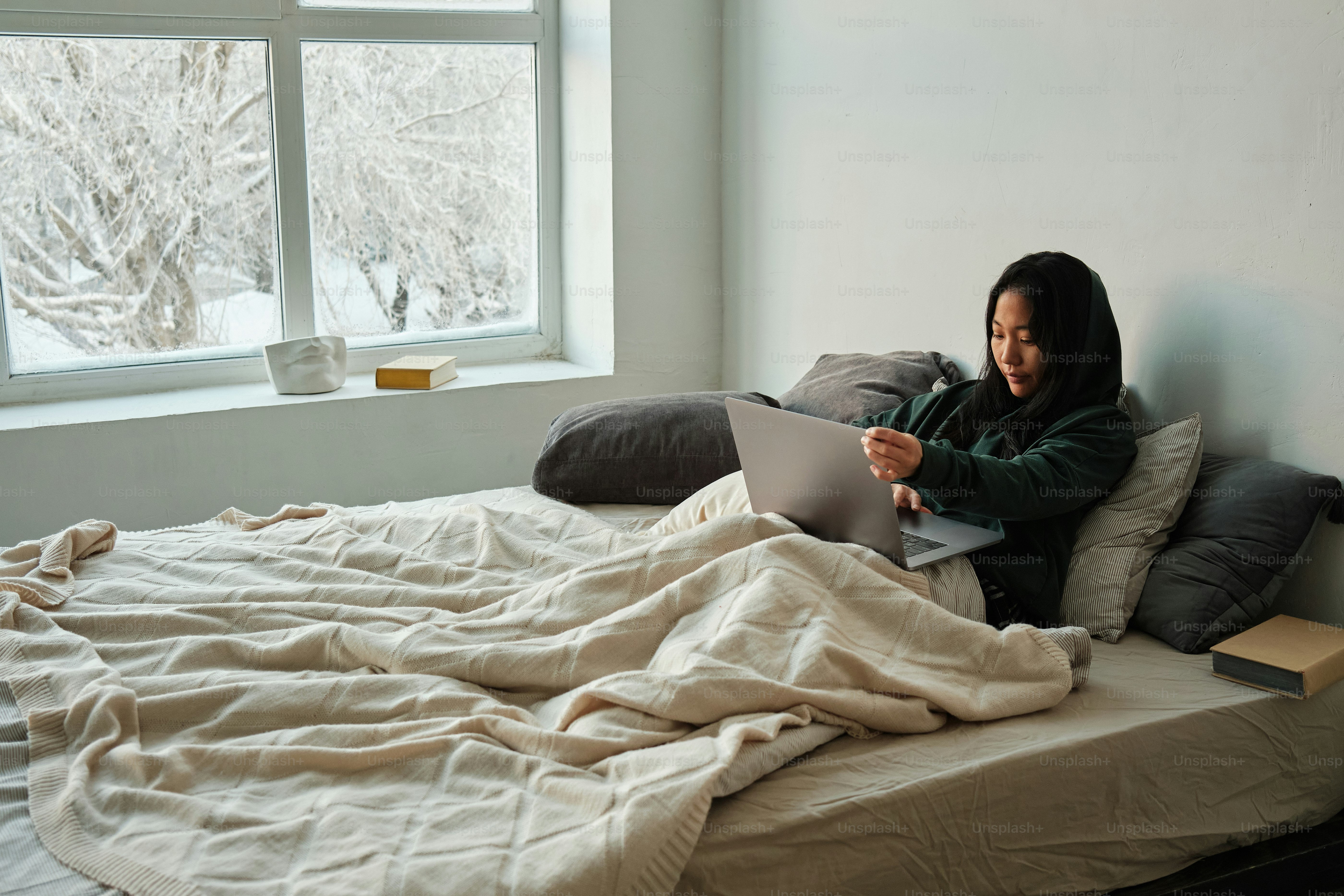 eine Frau, die auf einem Bett sitzt und einen Laptop benutzt