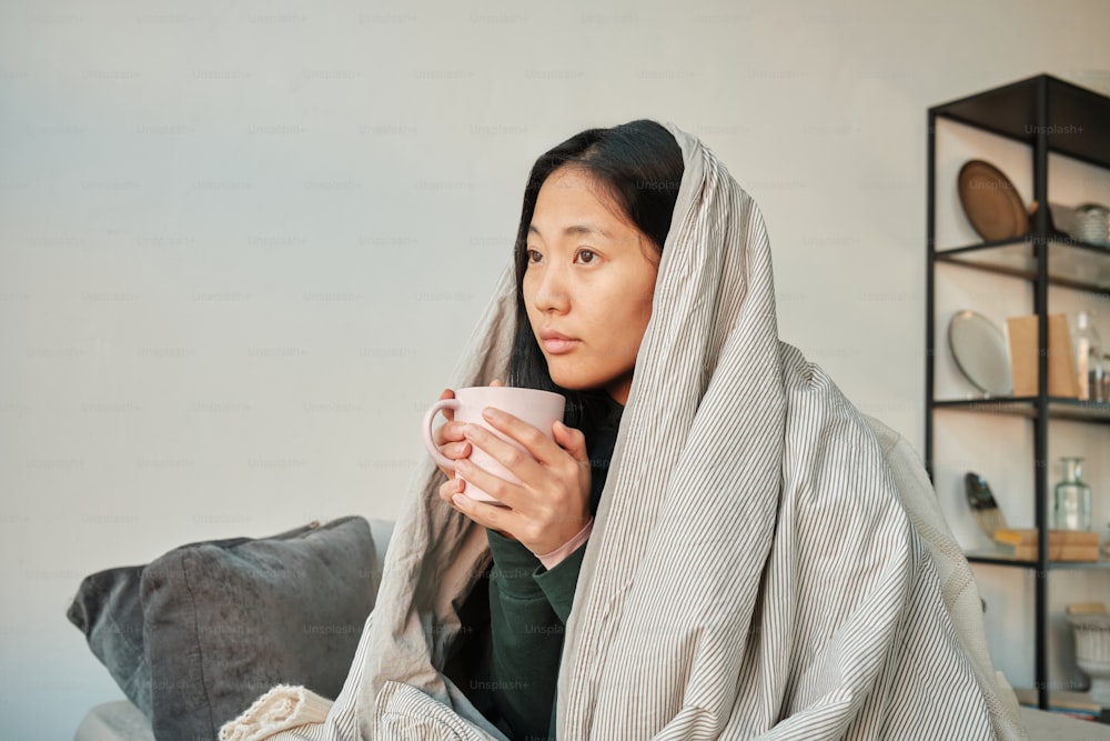 une femme assise sur un canapé tenant une tasse de café