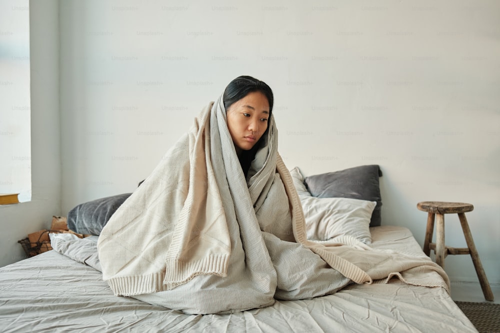 a woman wrapped in a blanket on a bed