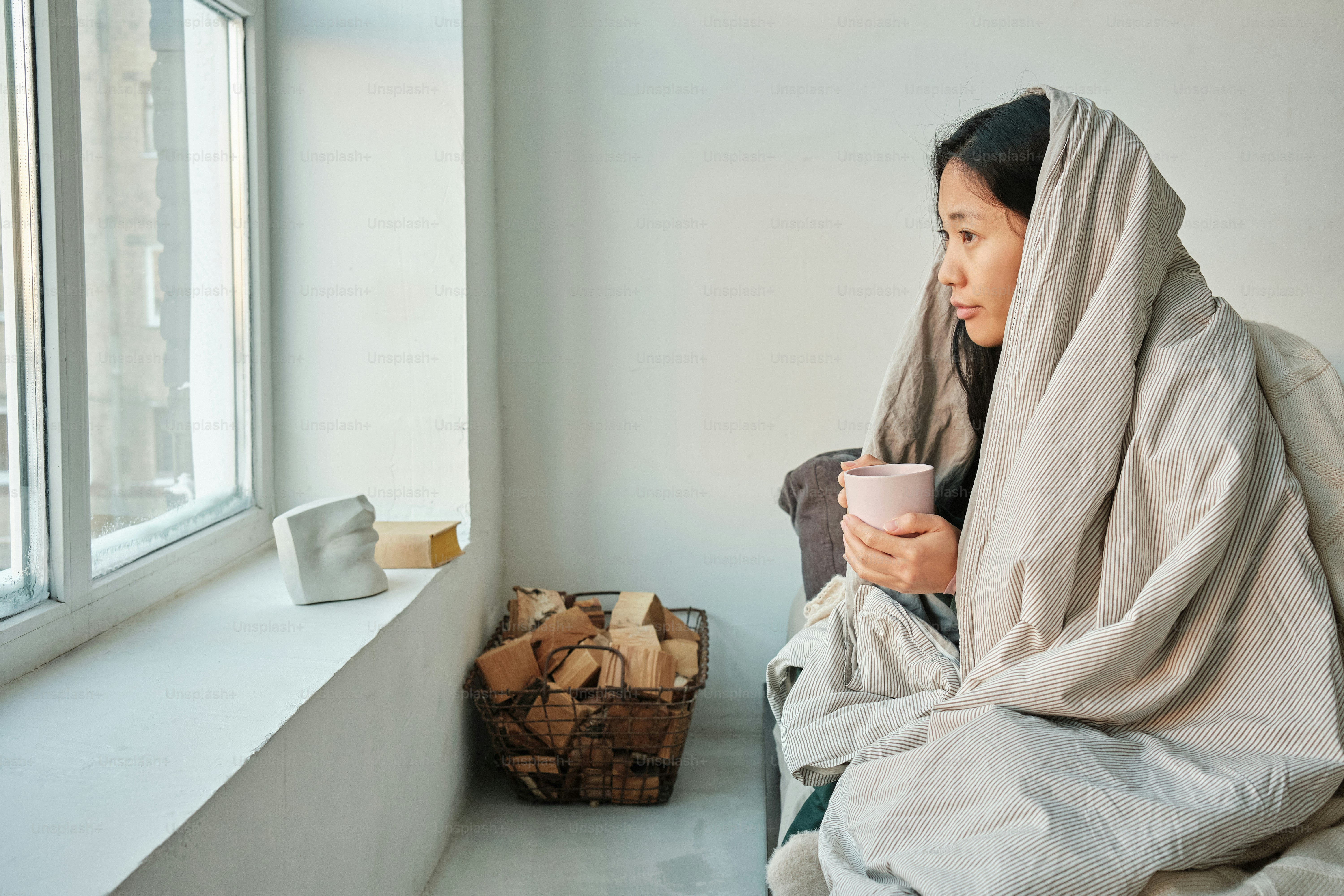 a woman sitting on a window sill holding a cup of coffee