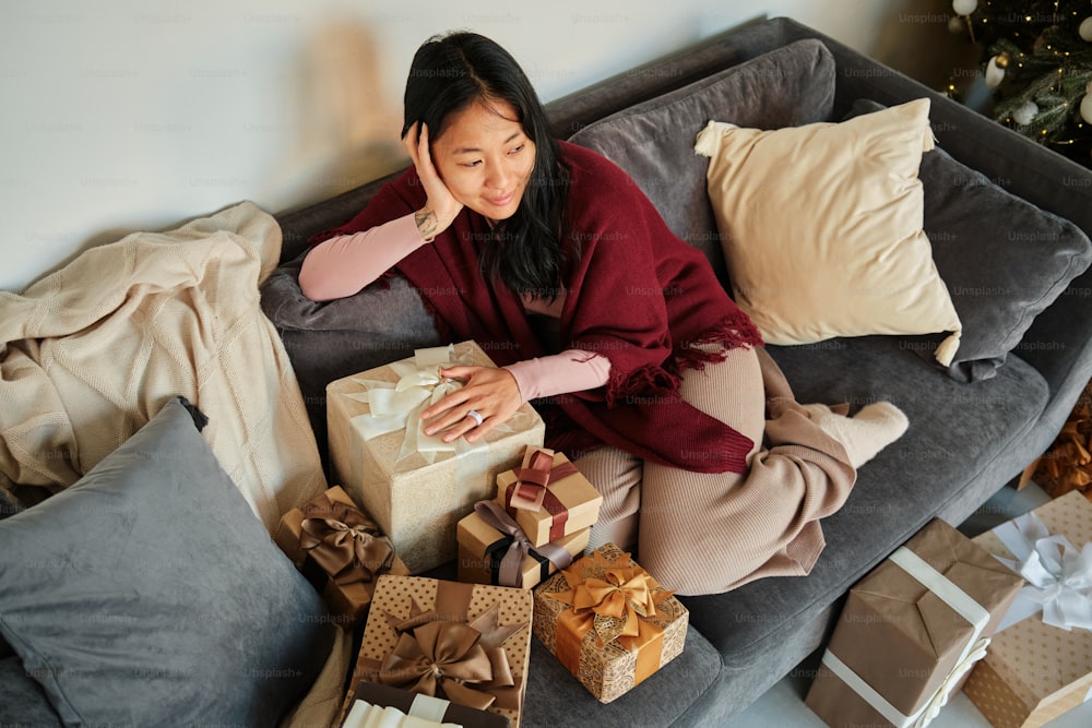 a woman sitting on a couch surrounded by presents