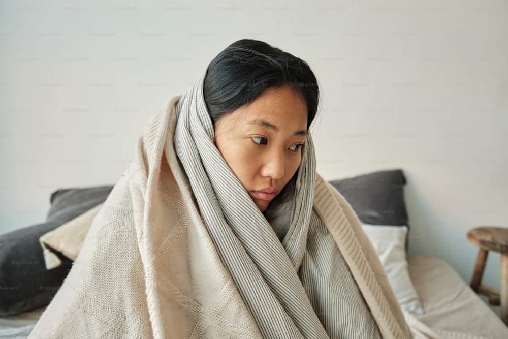 a woman wrapped in a blanket on a bed