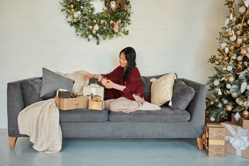 a woman sitting on a couch in front of a christmas tree