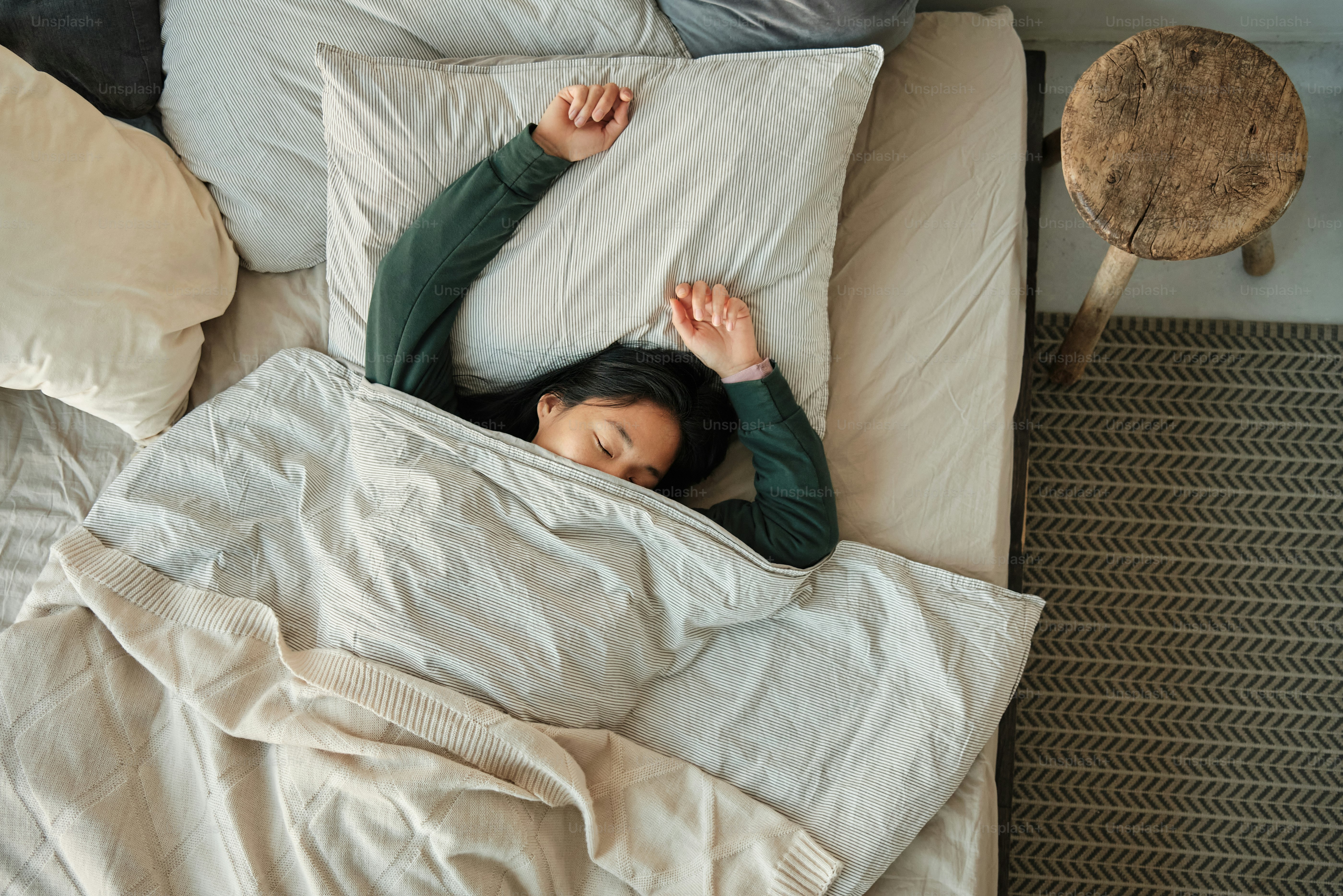 asian girl sleeping in bed wrapped in a blanket