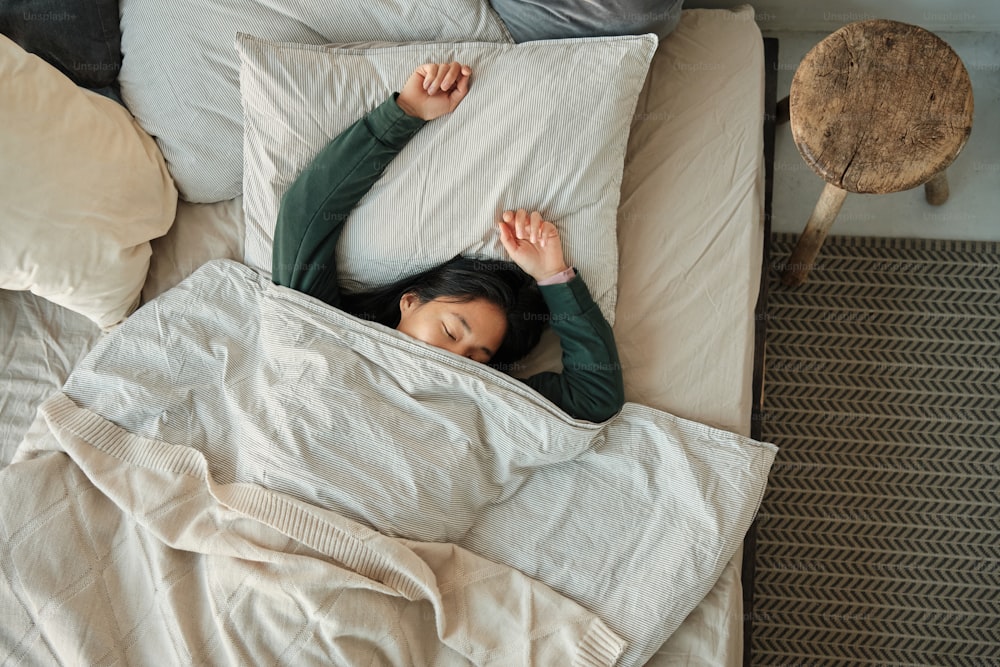 a woman laying in bed under a blanket