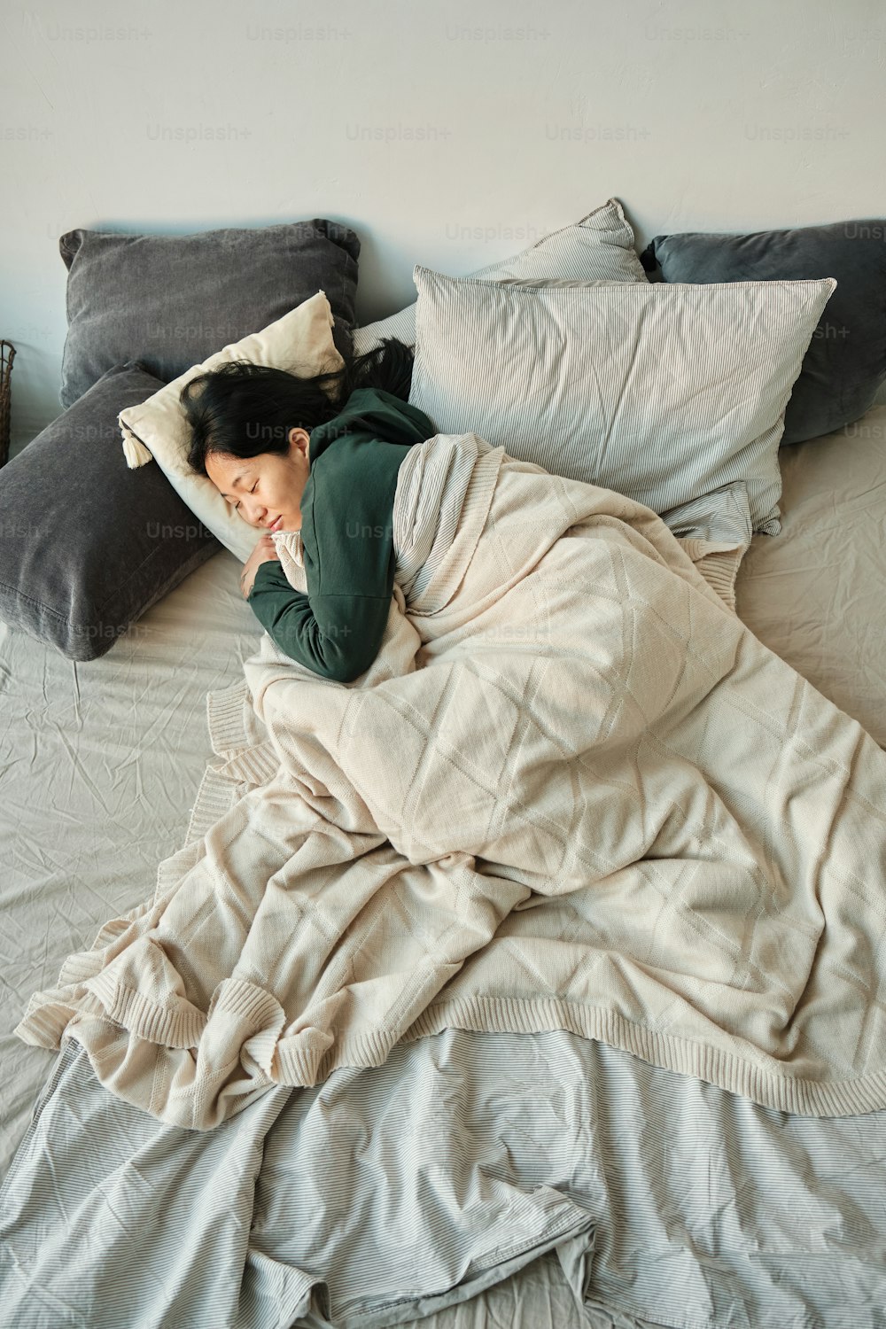 a woman is sleeping on a bed with a lot of pillows